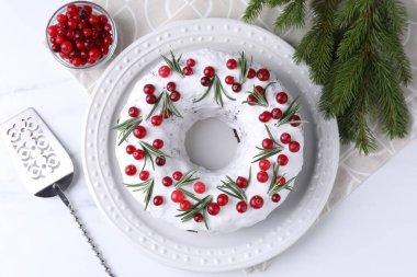 Beyaz masa üzerinde yaban mersinli, biberiyeli ve köknar dallı lezzetli bir Noel pastası.