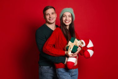 Noel hediyeli mutlu çift ve kırmızı arka planda dekoratif şeker kamışı