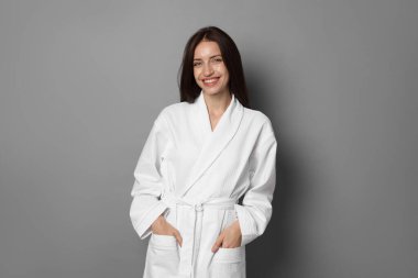 Gri arka planda bornoz giyen güzel bir kadın.