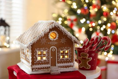 Güzel zencefilli kurabiye evi, mücevherler ve şeker kamışları kapalı mekandaki bulanık ışıklara karşı, yakın çekim. Noel atmosferi