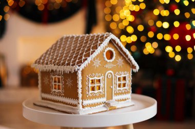 Beyaz masadaki güzel zencefilli kurabiye evi kapalı alanda bulanık ışıklara karşı, yakın çekim