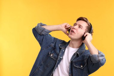 Kulaklıklı adam sarı arka planda müzik dinliyor. Metin için boşluk