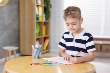 İçerideki ahşap masada resim yapan sevimli küçük çocuk. Metin için boşluk