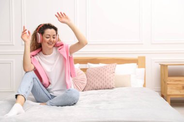 Evdeki beyaz duvarın yanında kulaklıklı mutlu kadın dans ediyor. Metin için boşluk