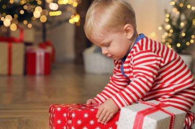 Noel pijamalı bebek hediye kutusunu içeride açıyor.