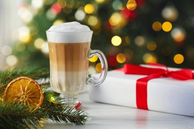 Beyaz ahşap masada bulanık ışıklara karşı Aromatik kahve ve Noel dekoru, yakın plan.