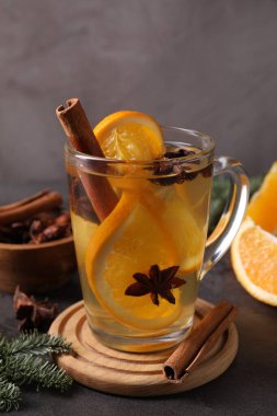 Lezzetli, portakal, baharat ve köknar dallı beyaz şarap koyu dokulu masa üzerinde gri arka planda, yakın plan