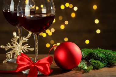 Kırmızı şarap kadehleri ve ahşap masanın üzerinde arka planda bulanık ışıklar, yakın plan.