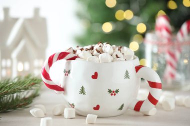 Lezzetli kakao, şekerleme çubuğu ve Noel süsü beyaz masada bulanık arka planda, yakın planda