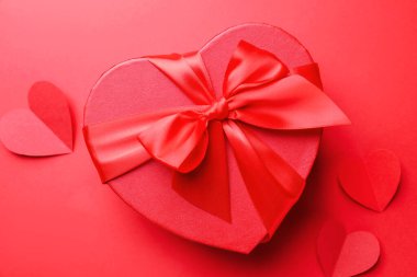 Sevgililer Günün kutlu olsun. Kalp şeklinde hediye kutusu ve kırmızı arka planda kağıt kalpler, düz yatıyordu.