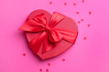 Sevgililer Günün kutlu olsun. Kalp şeklinde hediye kutusu ve pembe arka planda konfeti.