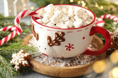 Lezzetli kakao, şekerleme kamışı, zencefilli kurabiye ve Noel süsü. Gri ahşap masa, yakın plan.