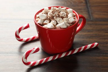 Lezzetli kakao, marşmelov ve şeker kamışları ahşap masada, yakın plan.