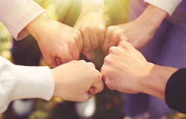 Güneşli bir günde dışarıda yumruk tokuşturan bir grup gönüllü, yakın plan. Pankart tasarımı