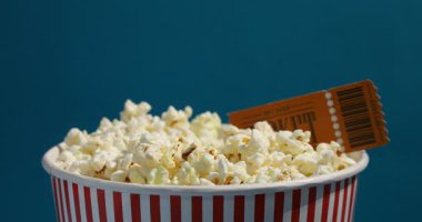 Açık mavi arka planda lezzetli patlamış mısır yiyen adam, yakın plan.