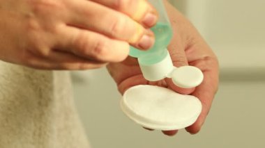 Kadın pamuk pedlere kozmetik ürünler koyuyor, yakın plan.