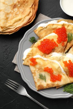 Lezzetli krepler kırmızı havyarlı ve ekşi kremalı siyah desenli masa, düz.