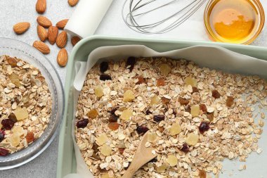 Tahıl yapıyorum. Yulaf ezmesi, kurutulmuş meyve, badem fıstığı ve balla bezenmiş düz bir kompozisyon.