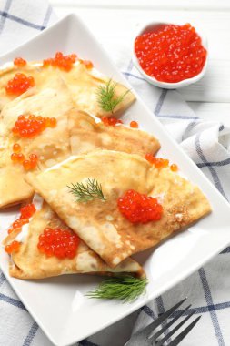 Kırmızı havyarlı leziz krepler ve beyaz ahşap masada ekşi krema.