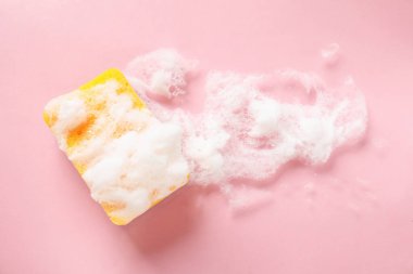 Pembe arka planda köpüklü mutfak süngeri.