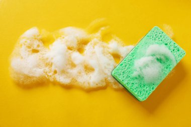 Turuncu arka planda köpüklü mutfak süngeri, üst manzara. Metin için boşluk