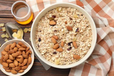Tahıl yapıyorum. Yulaf gevreği, kurutulmuş meyve, badem fıstığı ve bal ahşap masada, düz uzanmış.