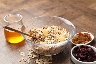 Tahıl yapıyorum. Kurumuş meyveli yulaf gevreği ve ahşap masada bal, yakın plan.