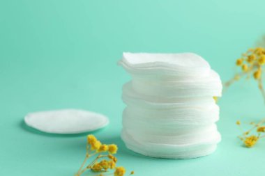 Turkuaz arka planda temiz pamuk pedleri ve çiçekler, yakın plan. Metin için boşluk