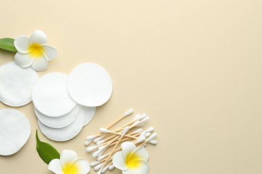 Temiz pamuk pedleri, bej arka planda bezler ve çiçekler, düz yatış. Metin için boşluk