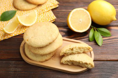 Lezzetli limonlu kurabiyeler ve ahşap masada meyve dilimleri, yakın plan.