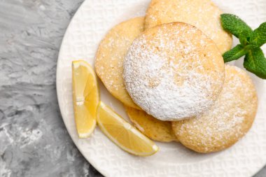 Lezzetli limonlu kurabiyeler ve meyve dilimleri gri masada, üst tarafta.