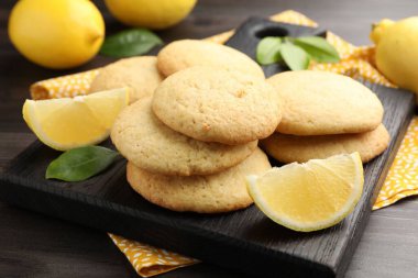 Lezzetli limonlu kurabiyeler ve koyu ahşap masadaki meyve dilimleri, yakın plan.