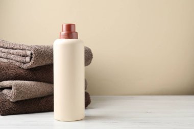 Çamaşır ve bir şişe deterjan beyaz ahşap masada bej arka planda, yakın plan. Metin için boşluk