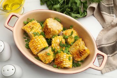 Beyaz masada yeşil soğanlı ızgara mısır koçanı parçaları.