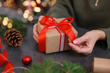 Gri masada Noel hediyesini paketleyen kadın, yakın plan.