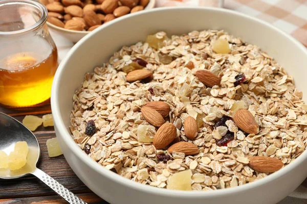 Tahıl yapıyorum. Yulaf gevreği, kurutulmuş meyve, badem fıstığı ve bal ahşap masada, yakın plan.