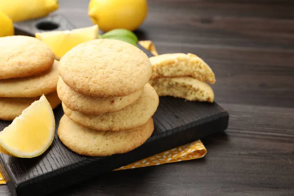 Lezzetli limonlu kurabiyeler ve koyu ahşap masada meyve dilimleri, yakın plan. Metin için boşluk