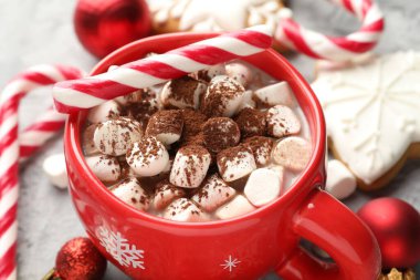 Marşmelovlu lezzetli kakao, baston şekerler, zencefilli kurabiyeler ve gri masada Noel dekoru, yakın plan.