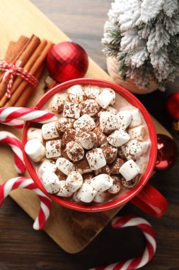 Marşmelovlu lezzetli kakao, baston şekerler, tarçın ve Noel süsü ahşap masada, düz uzanmış