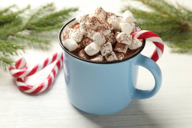 Marşmelovlu lezzetli kakao, baston şekerler ve beyaz ahşap masada Noel dekoru, yakın plan.