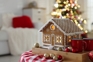 Güzel zencefilli kurabiye evi, kupalar ve takılar kapalı alanda bulanık ışıklara karşı, metin için yer ile yakın çekim. Noel atmosferi