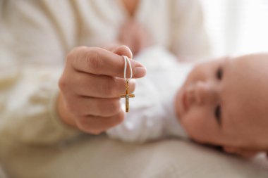 Vaftiz ayini. Kadın kucağında küçük bebek ve altın haç, seçici odaklanma