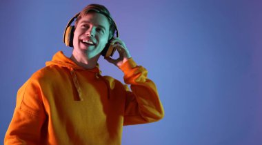 Kulaklıklı bir adam mavi arka planda neon ışıklarla müzik dinliyor. Metin için boşluk