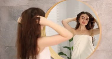 Banyoda aynanın yanında havluya sarılmış güzel bir kadın.