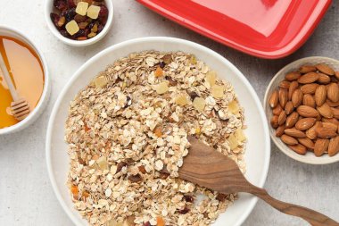 Tahıl yapıyorum. Bir kase yulaf ezmesi, bal ve kuru meyveler açık gri masada, düz yatıyordu.