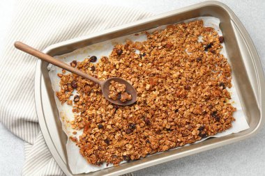 Lezzetli granola, kurutulmuş meyve ve tepside kaşık açık gri masa, üst manzara.