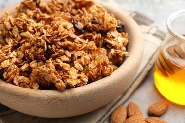 Kurumuş meyveli lezzetli granola ve açık gri masada bal, yakın plan.