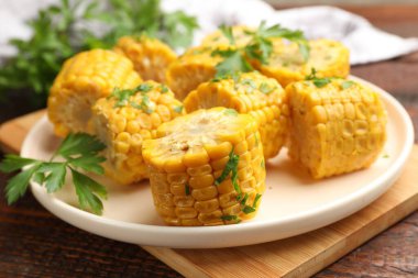 Ahşap masada maydanozlu haşlanmış mısır koçanı parçaları, yakın plan.