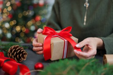 Gri masada Noel hediyesini paketleyen kadın, yakın plan.