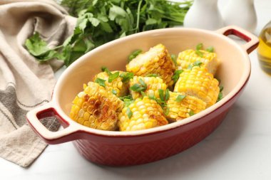 Beyaz masada yeşil soğanlı ızgara mısır koçanları, yakın plan.